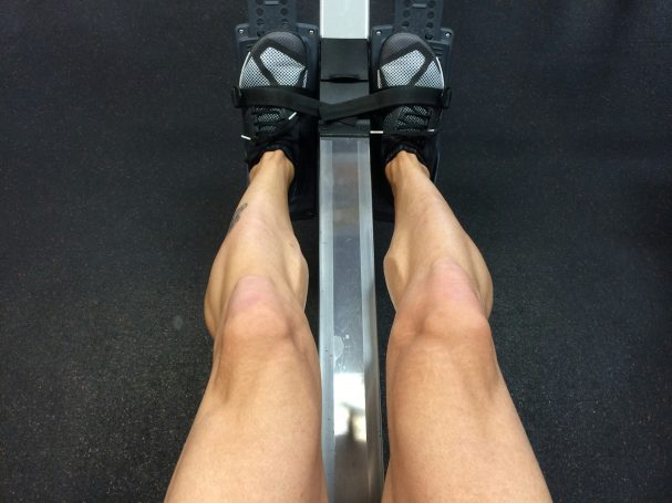 Beine auf einem Fitness-Gerät mit gefesselten Füßen.