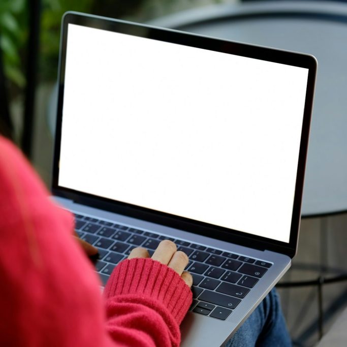 Eine Person tippt auf einem Laptop mit leerer Bildschirmoberfläche.