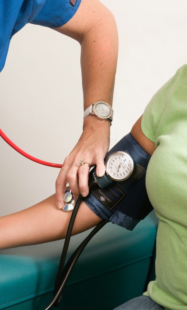 Eine Person misst den Blutdruck einer anderen Person mit einem sphygmomanometrischen Gerät.