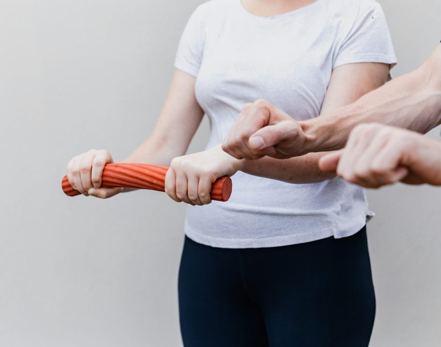 Physiotherapeut Lutherstadt Wittenberg Gymnastikball Ein Trainer unterstützt eine Frau bei einer Übung mit einer Rolle.